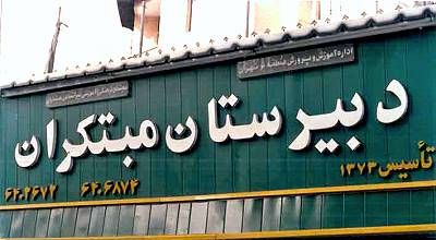 نمای بیرونی ساختمان دبیرستان با تابلوی نام مدرسه روی درب ورودی