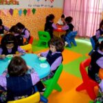 دانش‌آموزان پیش‌دبستانی در کلاسی رنگین مجهز به صندلی‌ها و میز‌های رنگی برای فعالیت‌های یادگیری