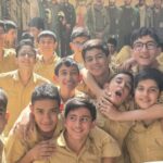 گروهی از دانش‌آموزان دبستان با لباس کاکی‌رنگ یکسان در حال پوز برای عکس دسته‌جمعی در مدرسه