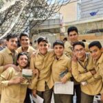 دانش‌آموزان پسر با لباس فردی در حیاط مدرسه در حین یک گردهمایی یا فعالیت گروهی