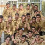 گروه دانش‌آموزان پسر در یونیفرم کاکی ایستاده در حیاط مدرسه برای تصویری یادگاری