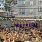 دانش‌آموزان و کادر آموزشی در حیاط مدرسه برای برگزاری مراسم و اجتماع جمعی با تزئینات موقت