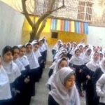 گروهی از دانش‌آموزان دختر در حجاب سفید در حیاط مدرسه در حال ایستادن و تجمع برای یک مراسم یا رویداد