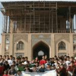 تجمع گروهی دانش‌آموزان و معلمان مقابل ساختمان تاریخی با معماری سنتی ایرانی در حین یک رویداد/مراسم