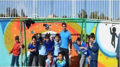 گروهی از دانش‌آموزان در حین فعالیت خارجی ایستاده در برابر دیوار رنگارنگ هنری