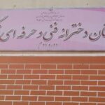 تابلوی فارسی ورودی مدرسه با نام و اطلاعات تاریخی بر روی دیوار آجری قرمز