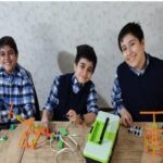 سه دانش‌آموز در حال فعالیت رباتیک با کیت Lego Mindstorms و تجهیزات STEM در کلاس