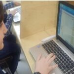 دانش‌آموز در حال کار و تایپ روی لپ‌تاپ کامپیوتر
