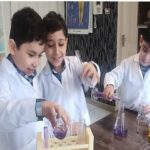 دانش‌آموزان درحال انجام آزمایش علمی با بطری‌های شیمیایی در آزمایشگاه مدرسه