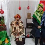 دو دانش‌آموز در میان نمایش تزئینات میوه‌ای و سازه‌های دکوری در مراسم شنبه کودک
