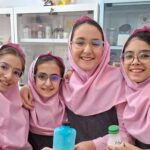 چهار دانش‌آموز دختر در لباس شنی مدرسه در کنار وسایل آزمایشگاهی؛ عکس یادگاری از فعالیت علمی