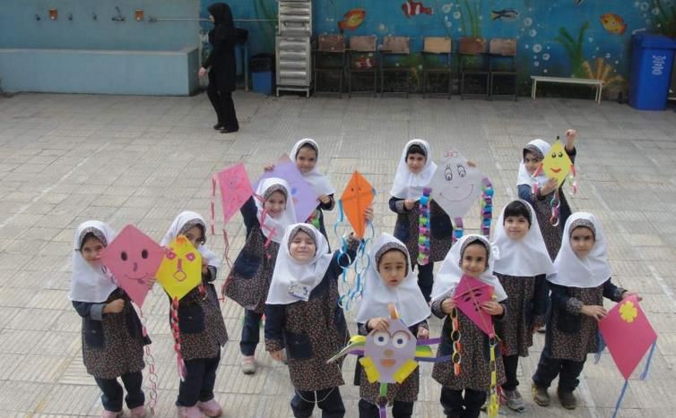 دانش‌آموزان دختر در حال نمایش بادکاک‌های رنگی کاغذی که در یک فعالیت یا رویداد آموزشی ساخته‌اند، حاضرند و چهره خندان دارند.