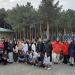دسته‌گل دانش‌آموزان و معلمان ایستاده در حیاط مدرسه برای عکس یادگاری رسمی