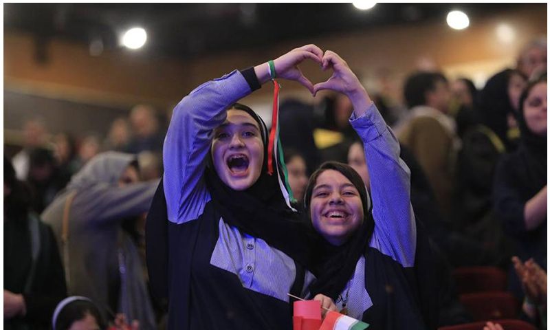 دو دانشآموز دختر در حال نشان دادن مدالهای ورزشی و تظاهر شادمانی در مراسم تقدیر مدرسه