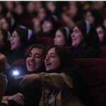 دانش‌آموزانی که با لذت در سالن سینما در حال تماشای فیلم هستند