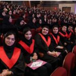 دانش‌آموزان با لباس رسمی و روسری قرمز در حال حضور در مراسم فارغ‌التحصیلی مدرسه در یک سالن تاتری