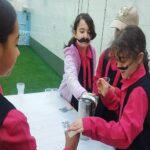 دانش‌آموزان دختر در حال انجام یک فعالیت تجربی علمی در حالی‌که روی یک میز کار می‌کنند و مواد آزمایشی را دستکاری می‌کنند.