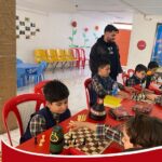 دانش‌آموزان در حال بازی شطرنج در کلاس درس با نظارت معلم