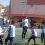 دانش‌آموزان مدرسه در حیاط در حال شرکت در فعالیت ورزشی و بدنی تحت نظارت معلم