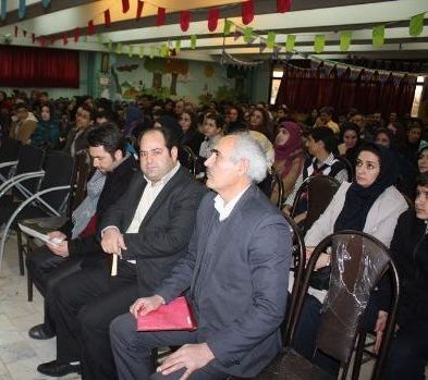 مراسم رسمی در سالن با حضور مسئولان و جمعیت، پرسونل و بزرگسالان روی صندلی