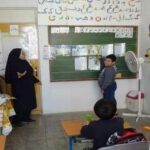 نمای داخلی کلاس درس با دانش‌آموزان و معلم، تابلوی سبز و میز و صندلی‌های مدرسه‌ای