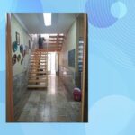 راهرو و عبور‌راه داخلی ساختمان مدرسه با درهای چوبی، دیوارهای روشن، کف سرامیک و پلکان