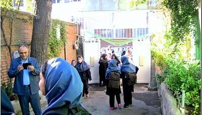 دسته‌ای از دانش‌آموزان در حال شرکت در یک برنامه‌ی گروهی در راهروی مدرسه، برخی با لباس ورزشی آبی رنگ