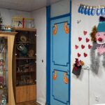 کلاسی تزیین‌شده برای جشن با بالن‌های رنگی، دکوراسیون‌های کاغذی آویزان، عروسک‌های دست‌ساز، و قلب‌های قرمز