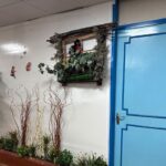 راهرو مدرسه با تزئینات گل‌های مصنوعی و درب آبی رنگ