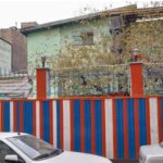 نمای بیرونی سردر و ورودی ساختمان با دیوار رنگی آبی، قرمز و سفید و پنجره‌های نقره‌ای