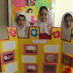 سه دانش‌آموز پشت پوستر زرد رنگ با محتوای آموزشی در حال نمایش یک پروژه گروهی در کلاس