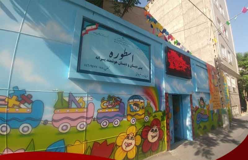 نمای بیرونی ساختمان مدرسه با درب ورودی آبی‌رنگ و تابلو نام‌نوشته طوره روی دیوار