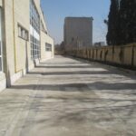 حیاط مدرسه با پوشش بتنی و ساختمان اصلی مجاور