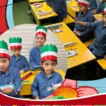 دانش‌آموزانی در حال غذا خوردن در مراسم جشن ملی، با تاج کاغذی به رنگ پرچم ایران، نشسته در کنار میزهای زرد سالن غذاخوری مدرسه