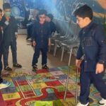 دانش‌آموزان در حال شرکت در یک فعالیت بازی تعاملی یادگیری با خانه‌های شماره‌دار روی زمین در سالن مدرسه