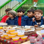 دانش‌آموزان مدرسه در جشنواره غذایی با نمایش غذاهای محلی و سنتی ایرانی در حیاط مدرسه