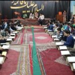 دانش‌آموزان مدرسه پیام قادر در حال شرکت در مراسم و جمع‌اندیشی داخل سالن با پارچه‌نوشته و تزئین‌های موقت