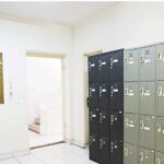 راهروی مدرسه با ردیف‌های صندوق‌های شخصی سفید و سیاه برای نگهداری وسائل دانش‌آموزان، تابلوی اطلاعاتی در سمت چپ