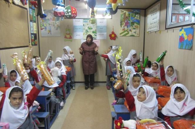 گروهی از دانش‌آموزان دختر در حال انجام فعالیت خلاقانه و هنری گروهی در کلاس درس تحت راهنمایی معلم