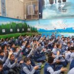 دانش‌آموزان جمع‌شده در حیاط مدرسه با دیوار نقاشی‌شده زمینه آسمان و طبیعت