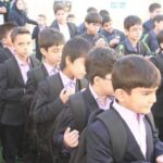 دانش‌آموزان مدرسه در لباس رسمی حاضر در یک مراسم یا رویداد مدرسه‌ای در حیاط یا فضای باز