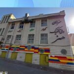 نمای بیرونی ساختمان مدرسه پلی‌تکنیک هنر با دیوار خاکستری و پلاکات رنگی و پنجره‌های متعدد