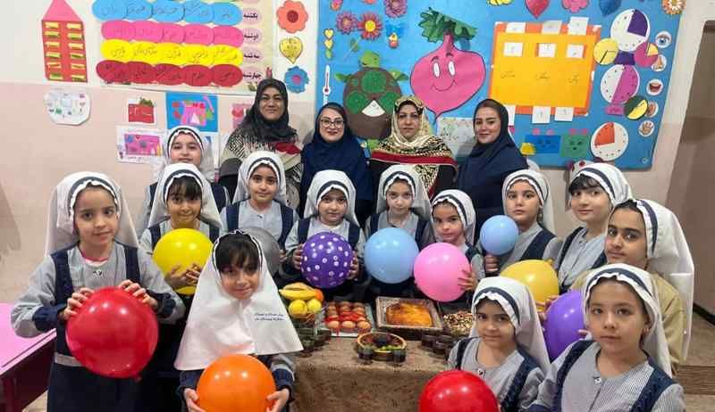 دانش‌آموزان دختر در کلاس درس در حال برگزاری مراسمی آموزشی با حضور معلم و بادکنک‌های رنگی