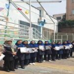 گروهی از دانش‌آموزان و معلمان در حیاط مدرسه، حین دریافت و نمایش مدارک پایانی دوره در مراسم تقسیم‌گری