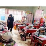 دانش‌آموزان در حال درس خواندن در کلاس‌درسی که با میزهای قرمز و تزیینات رنگارنگ تهیه شده‌است