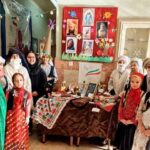 دانش‌آموزان و بزرگسالان در لباس‌های سنتی ایرانی حول میز تزئین‌شده در حین جشن فرهنگی درون کلاس درس