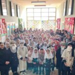 دسته‌ی جمعی دانش‌آموزان و معلمان مدرسه در یک مراسم رسمی داخل راهروی ساختمان