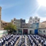 دانش‌آموزان در حیاط مدرسه به‌ صورت تشکیل‌دهنده‌ی منظم در طول مراسم صبحانه‌ی مدرسه