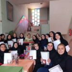دانش‌آموزان دختر در حال دریافت گواهینامه و نشان تقدیر در مراسم اختتامی مدرسه، در حالی‌که جوایز و گواهینامه‌های تقدیر در دست دارند