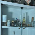 کابینت شیشه‌ای آزمایشگاه با بطری‌های شیمیایی، نمونه‌های آزمایشی و ابزارهای علمی